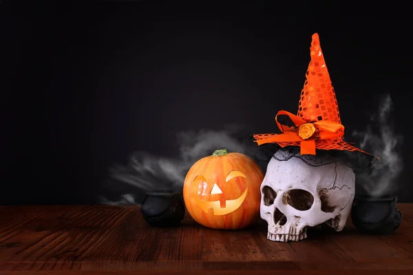 holidays halloween concept image. Pumpkin and skull over wooden table and black background