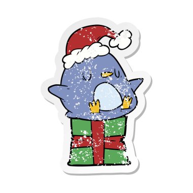 hediye üzerinde oturan bir sevimli çizgi penguen sıkıntılı etiket