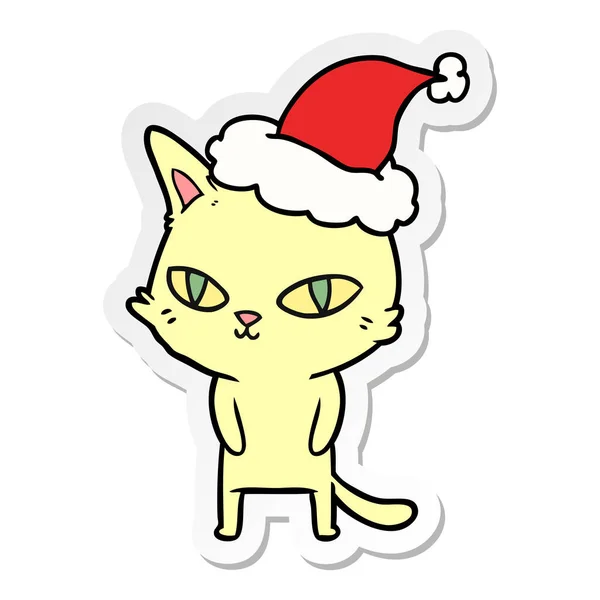 Desenho animado etiqueta de um gato com olhos brilhantes usando chapéu de santa —  Vetores de Stock