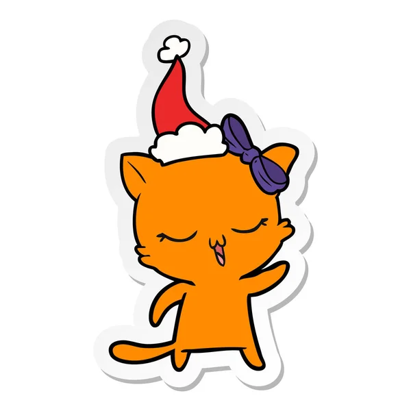 Autocollant dessin animé d'un chat avec arc sur la tête portant un chapeau de Père Noël — Image vectorielle