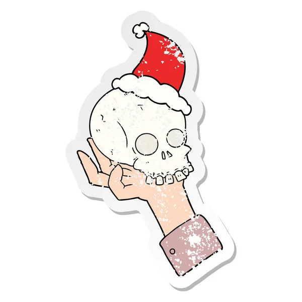 Distressed sticker cartoon of a hand holding skull wearing santa — Stock Vector