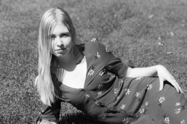 Girl are sitting on the green grass on the background of trees