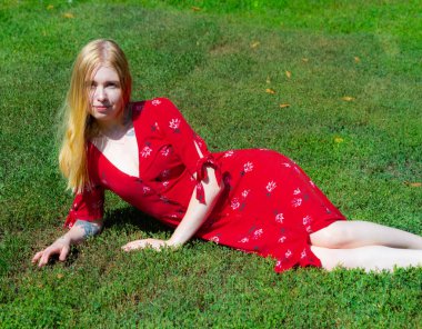 Girl are sitting on the green grass on the background of trees