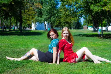 İki kızın ağaçları zemin üzerine yeşil çimenlerin üzerinde oturuyorsun