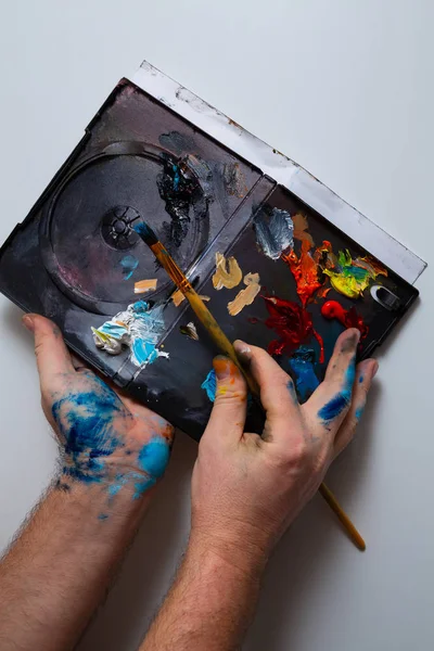 The hands of the artist soiled in paint