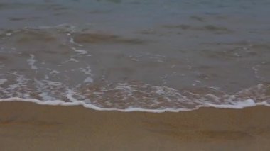 Adam kumlu plajda deniz tarafından sığ suda yürüyüş