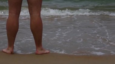 Adam kumlu plajda deniz tarafından sığ suda yürüyüş