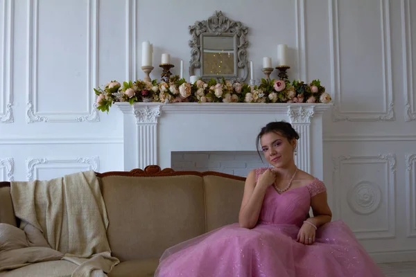 年轻美丽的女模特坐在粉红色礼服在室内工作室的时尚肖像 — 图库照片
