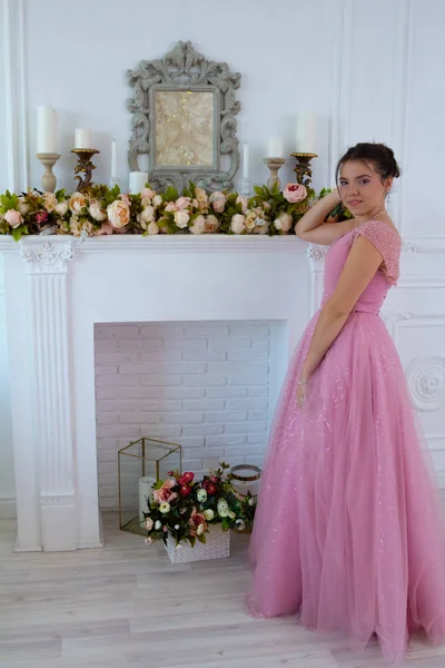 İç stüdyoda pembe elbise genç güzel kadın model ayakta moda portre.