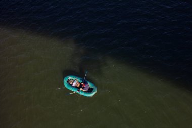 Nehirde yüzen bir teknede bir balıkçı