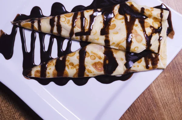 Bir çikolata tepesi beyaz bir tabakta tatlı krep