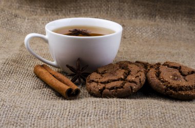 Bir fincan çay ve bir çuval bezi üzerine tarçın ile çikolata kurabiye