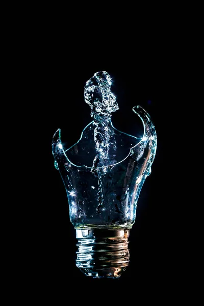 Creative broken light bulb with water fountain on isolated black