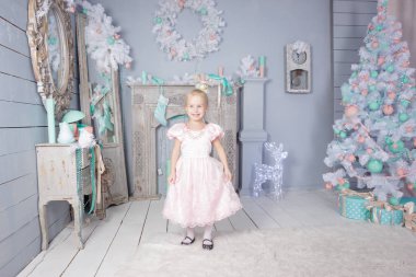 Avrupa küçük sarışın Prenses ile şirin kız taç Noel yerde oyuncak ve Noel ağacı ile dekore edilmiş Studio'da güzel elbiseli portresi