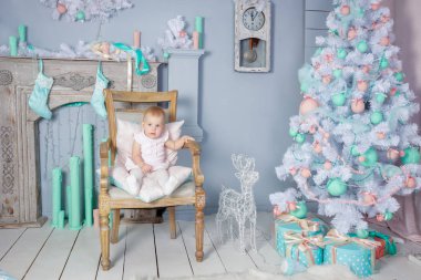 Sevimli küçük bir Avrupa Sarışın Prenses kız güzel bir elbise bir stüdyo vintage bir sandalyede oturan bir taç ile portresi Noel tema oyuncaklar, Noel ağacı ve şömine ile dekore edilmiş