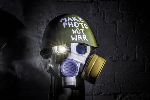 art picture of military gas mask and green helmet on white brick wall with shadows, the inscription make photo not war on fatherland defender day. concept of calling world peace without hatred and war