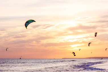 profesyonel kiters slayt dalgaları, aşırı grup atlar hava Karadeniz üzerinde yelken kanat liderliğindeki eller rüzgar ile bir gün batımı, onlookers fotoğrafçılar martı kıyısında. duyuru köyü. arkadan aydınlatmalı tonda,