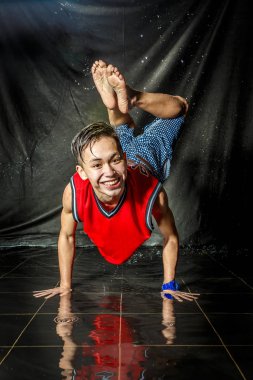 Koreli genç adam serin ve mutlu break dansçı karmaşık su sıçramalarına ve aqua bölge fotoğraf stüdyosu izole siyah arka plan ile sıvı damla etkileri ile katta yapan bboying tarzı