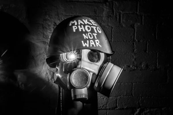 Art picture of military gas mask and green helmet on white brick wall with shadows, the inscription make photo not war on Fatherland defender day. concept of calling world peace without hatred and war