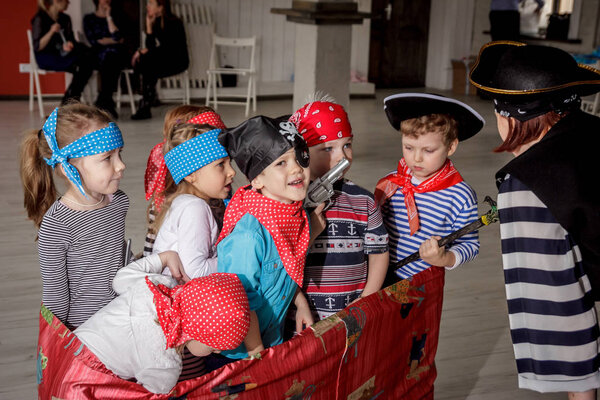 RUSSIA, YAROSLAVL - 17 FEB. 2018: happy group of children at a birthday celebration dressed in the style of pirates with an animator, contests and bubbles play games in a large room with loft style