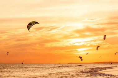 profesyonel kiters slayt dalgaları, aşırı grup atlar hava Karadeniz üzerinde yelken kanat liderliğindeki eller rüzgar ile bir gün batımı, onlookers fotoğrafçılar martı kıyısında. duyuru köyü. arkadan aydınlatmalı tonda,