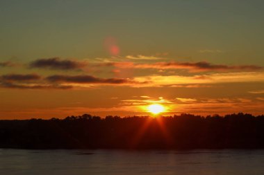 Güneş parlama ile bir nehir Volga yaz güneşin turuncu ışınları vurgular ile güzel derin sabah şafak.. Turuncu renkli ve arkadan aydınlatmalı tonlu.