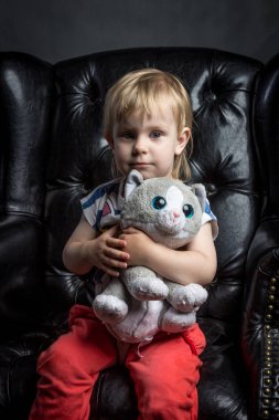 komik şirin bebek kiti kız portre Studio siyah izole arka plan siyah deri sandalyede oturan yumuşak oyuncak ile kırmızı pantolon farklı duygular ile