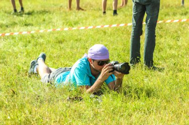Rusya, Yaroslavl - 30 Haziran 2012: yaz orman çadır kampında elinde bir kamera ile ciddi adam fotoğrafçı parlak Güneşli gün yarışmalara katılmak volga nehir bankalarda aktif oyunlar oynamak