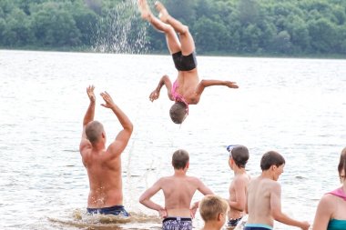 Rusya, Yaroslavl-30 Haziran 2012: Grup mutlu çocuklar ve yetişkin gençler yaz orman çadır kampı su atlama bankalar Volga Nehri üzerinde parlak güneşli bir gün yarışmalara katılmak bankaların aktif oyunlar oynamak