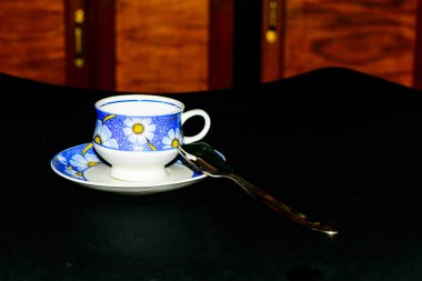 Koyu arka planda kaşıkla plaka üzerinde tek kahve fincanı