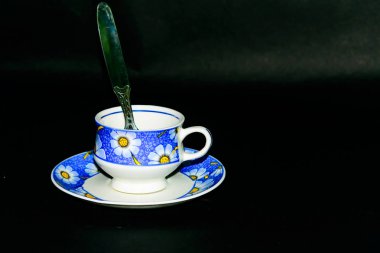 Koyu arka planda kaşıkla plaka üzerinde tek kahve fincanı