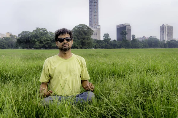 在公园做瑜伽 坐在绿草上的莲花姿势的资深大胡子男子 平静和冥想的概念 戴墨镜的年轻人在公园里沉思 Moidan 加尔各答 — 图库照片