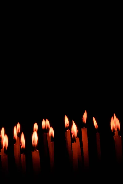 许多圣诞蜡烛在夜晚在黑色的背景上燃烧 蜡烛的火焰被隔离在黑色背景中 一组燃烧的蜡烛在黑暗中浅浅的田野深处 自由空间 — 图库照片