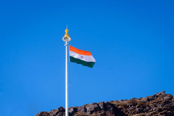 Indian tricolor national flag on a flagpole, waving in wind on mountain top. Blue sky background. Isilated Close up. 26 January Republic day, 15 August Indian Independence day, Travel tourism concept