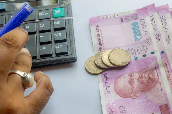 Mano recortada de una mujer cuenta corriente con calculadora y sosteniendo un bolígrafo. Los billetes y monedas de la India están en el lado de la mesa. Concepto de empresa. — Foto de Stock