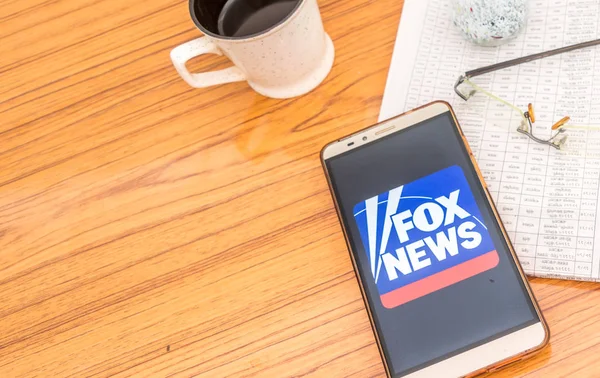 Kolkata, indien, 3. februar 2019: fox news app (anwendung) sichtbar auf dem handybildschirm schön platziert über einem holztisch mit zeitung und kaffee. ein Technologie-Produkt-Shooting. — Stockfoto