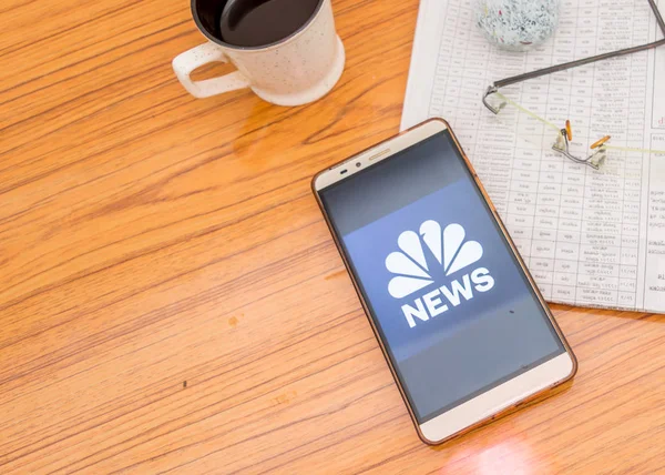 Kolkata (Inde), le 3 février 2019 : Application de nouvelles NBC (application) visible sur l'écran du téléphone mobile superbement placé sur une table en bois avec un journal et une tasse de café. Un tir de produit technologique . — Photo