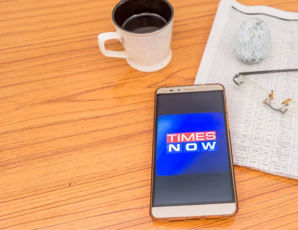 Kolkata (Inde), le 3 février 2019 : L'application Times Now est visible sur l'écran d'un téléphone portable superbement placé sur une table en bois avec un journal et une tasse de café. Un tir de produit technologique . — Photo