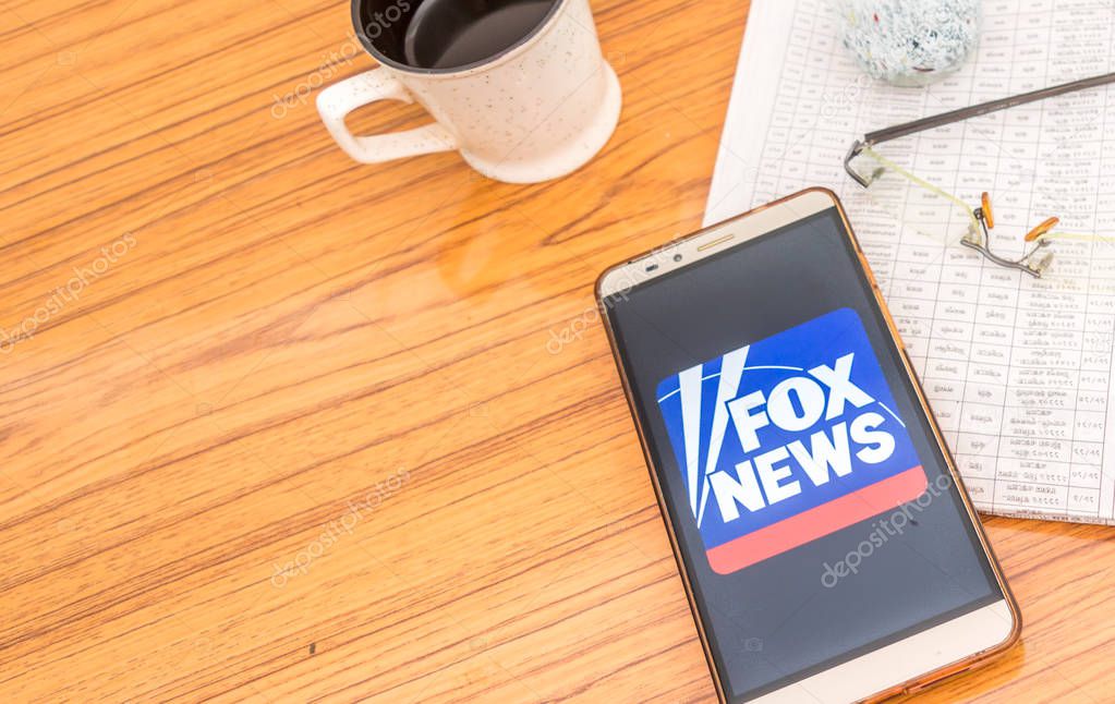 Kolkata, India, February 3, 2019: Fox news app (application) visible on mobile phone screen beautifully placed over a wooden table with a newspaper and a cup of coffee. A Technology Product Shoot.