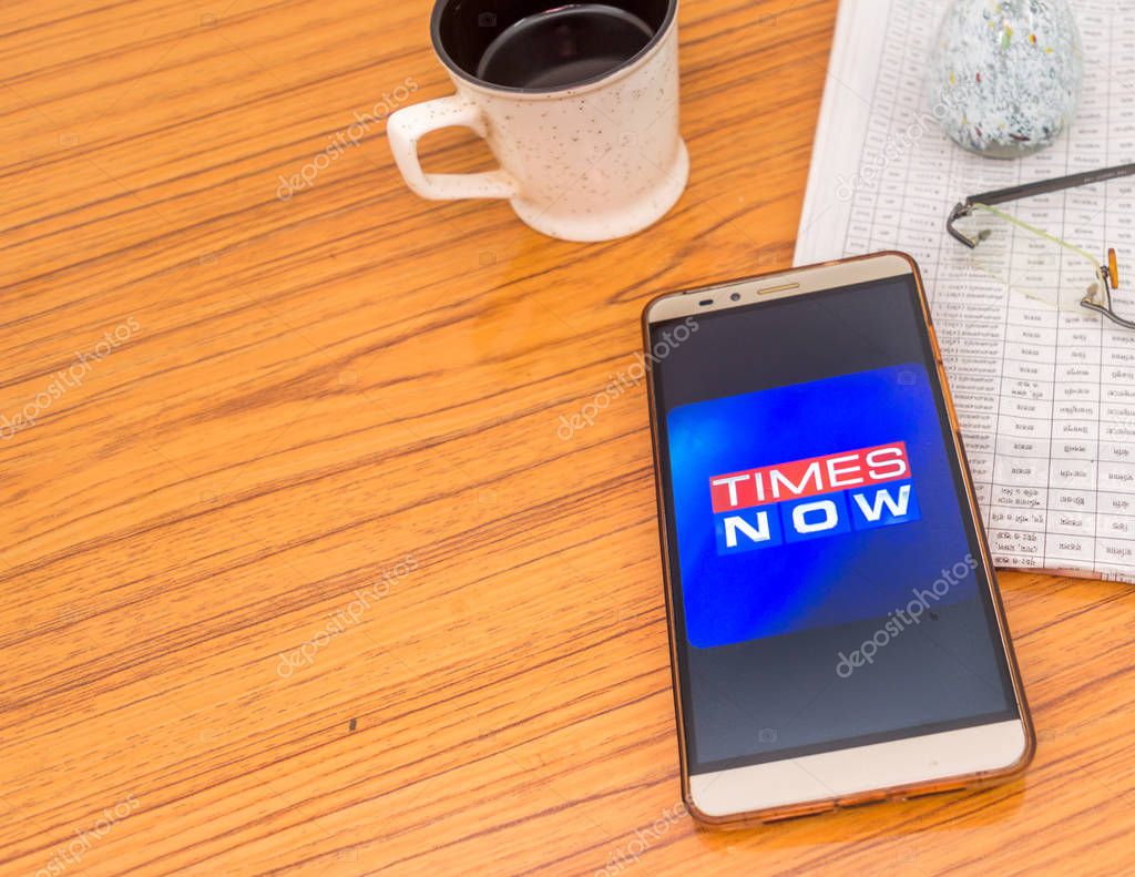 Kolkata, India, February 3, 2019: Times Now news app (application) visible on mobile phone screen beautifully placed over a wooden table with a newspaper and cup of coffee. A Technology Product Shoot.