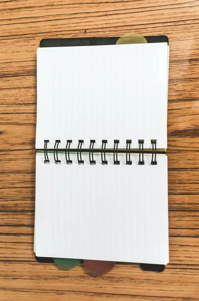 Bloc de notas vacío en una mesa de madera. Imagen de vista superior del cuaderno de planificador de bolsillo abierto con páginas vacías listas para agregar texto o maqueta. —  Fotos de Stock