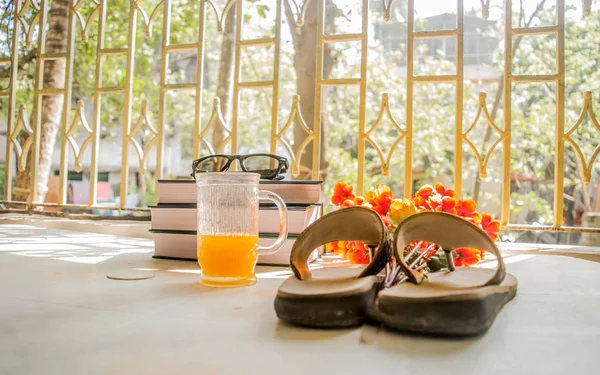 Modern women holiday essential for sunday summer time weekend activities on wooden table. Sunglasses placed over Books, flip flops, cocktail glass and flower bouquet with natural sunlight coming into — Stock Photo, Image