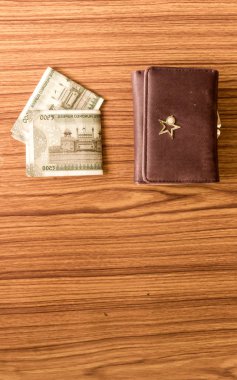 Ahşap bir masada kahverengi cüzdan deri çanta içinde Hint 500 rupisi nakit para. İş ekonomisi konsepti. Görüntünün ön tarafında metin için boşluk kopyalama odası olan yüksek melek görünümü