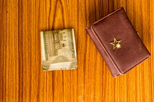 Indiske fem hundrede (500) rupee kontant note i brun farve tegnebog læder pung på et træbord. Erhvervsøkonomi koncept. Høj engel visning med kopiplads til tekst på nederste side af billedet - Stock-foto
