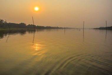Hindistan 'ın en kutsal nehrinin yansımasıyla çarpıcı, doğal, dramatik, yakıcı bir gün batımı. Ganj deltası Sunderbans, Batı Bengal, Hindistan' da..