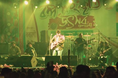 Kolkata India 1 Mayıs 2019 - Gitarist, önünde parlak renkli sahne ışıkları ve hayranları ya da tezahürat yapan kalabalık ile rock konser mekanı yapıyor. Yaz müziği şenlikli arka plan konsepti.