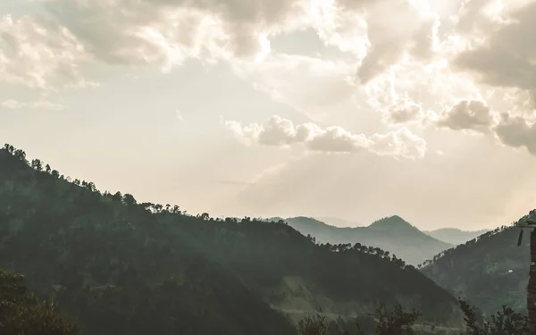 Панорама зимней Аннапурны, непальской горной долины в облаках и тумане. Солнечный луч света спускается из дождевого облака во время захода солнца. Штормовая погода, яркое солнце и копировальное пространство . — стоковое фото