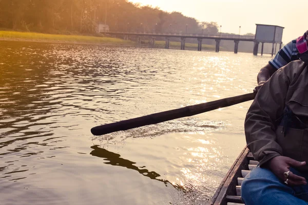 Rijd in een boot op een meer tijdens een prachtig gouden uur in romantische zonsondergang. Toeristische mensen ontspannen op het water. De prachtige natuur rond de achtergrond van de rivier en het instellen van de zon in de verte. Silhouet — Stockfoto