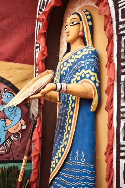 Bankura, West Bengal, India, mei 2018-standbeeld van een oude tribale vrouw staande op de binnenplaats met een bamboe "Kulo" in een modder hutten van een landelijk Indiaas dorp van West-Bengalen. Het toont traditionele Bengalen. — Stockfoto