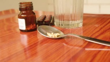 Antioksidan vitamin tableti, ilaç kabarcıkları, bir şişe ilaç, ölçüm kaşığında kapsül, masanın üzerine bir bardak su. Tıbbi eczane teması. Yan görünüm, kopyalama alanı ile kapat.